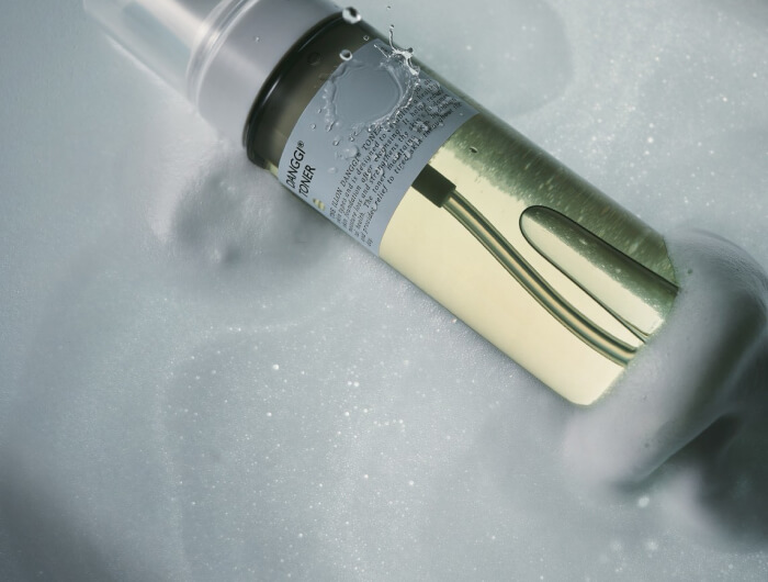 ガラスボトルに入った透明な美容液。水滴が付いた清潔感のあるスキンケア製品